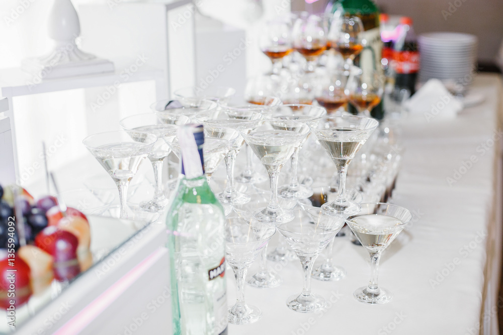 Pyramids of glasses with whisky and martini stand on white dinne
