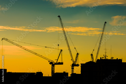 Silhouette of the tower crane on the construction site with city