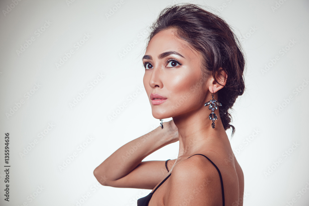 Glamour portrait of beautiful woman with earrings and fresh daily makeup on grey background. Glamour portrait of beautiful woman with earrings and fresh daily makeup on grey background.
