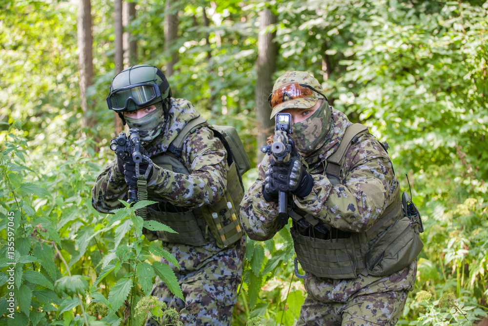 Military man in camouflage with guns in the woods