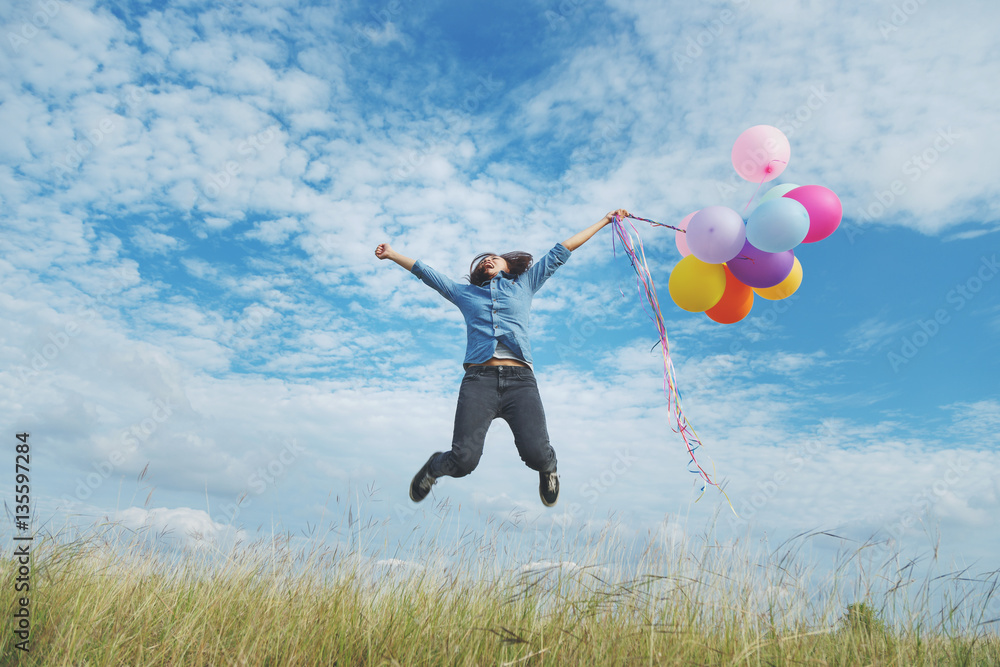 Beautiful woman at meadow with balloons in hand.