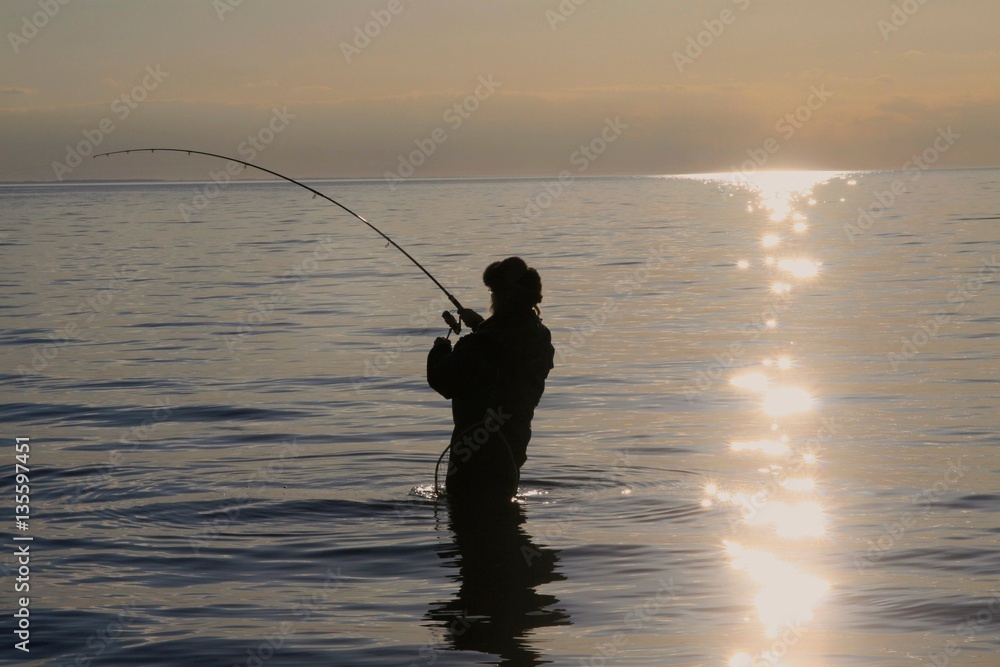 Meerforellenangler am Flügger Strand an der Ostsee im Abendlicht im Drill mit einer Meerforelle Meerforellenangler am Flügger Strand an der Ostsee im Abendlicht im Drill mit einer Meerforelle