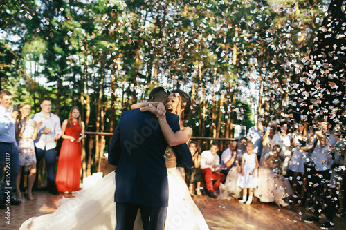 White confetti falls over wedding couple dancing on the porch © IVASHstudio