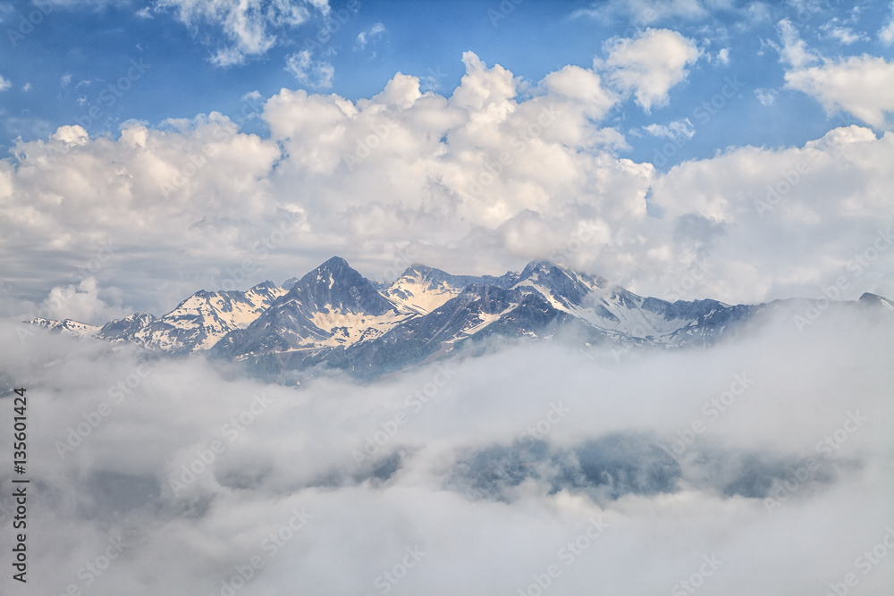 Beautiful scenic spring mountain landscape of snowy Aibga mountain peak with blue sky and clouds. Distant mountain tops scenery