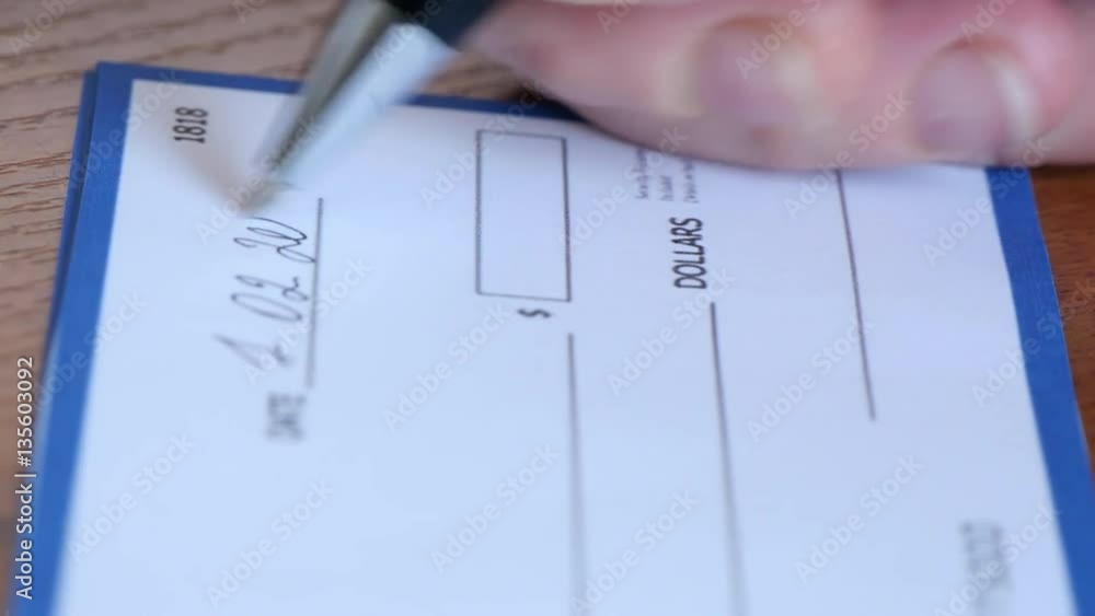 Close-up of human hand filling check. Check was designed by me, it is fake. The name signature etc are all fake. Close-up of human hand filling check. Check was designed by me, it is fake. The name signature etc are all fake.