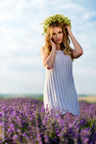 Beautiful Girl in lavender Field. Pretty woman Provence style in white dress and flowers wreath. Beautiful blonde woman in the lavender field on sunset Amazing portrait