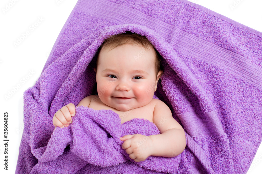 Newborn baby lying down and smiling in a purple towel Newborn baby lying down and smiling in a purple towel