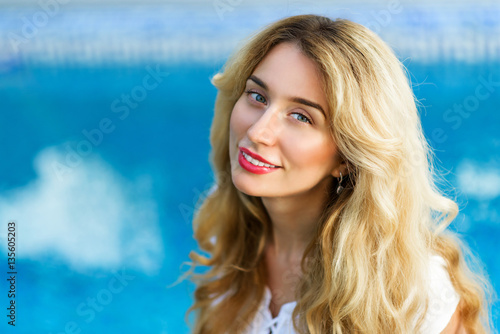 Happy young woman smiling. Curly blonde hair and red lips. Blue Background © castecodesign