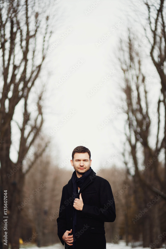 handsome and young man standing in the park alone handsome and young man standing in the park alone