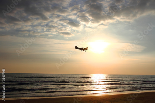 ultralight aircraft flying over the sea at sunset