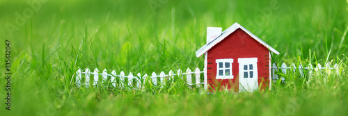 red wooden house model on the grass in garden photo