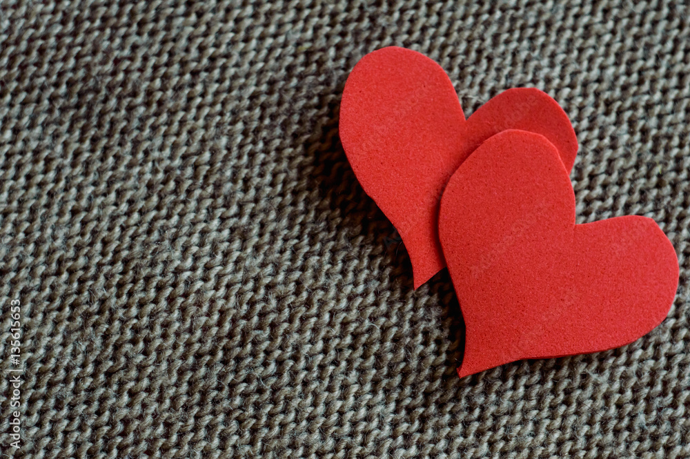 Fototapeta premium two red hearts wrapped in knitted fabric