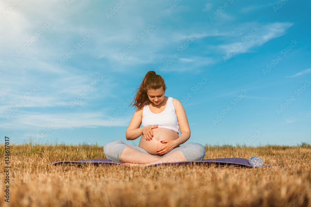 Pregnant woman exercising yoga on the mat Pregnant woman exercising yoga on the mat