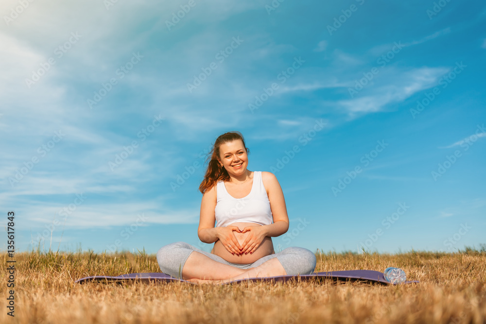Pregnant woman hands making heart shape on belly Pregnant woman hands making heart shape on belly