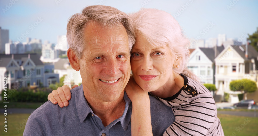 Senior couple sitting together at the park and smiling at camera