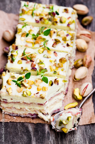 Slices  of layered cake with pistachio on wooden background