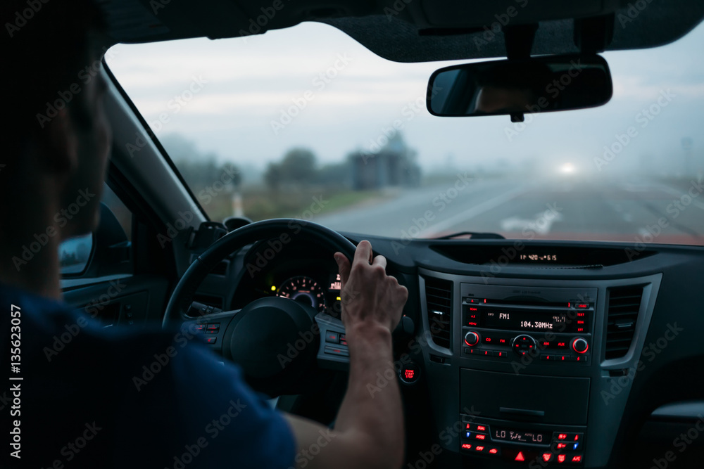 Man driving a car in fog. Back view
