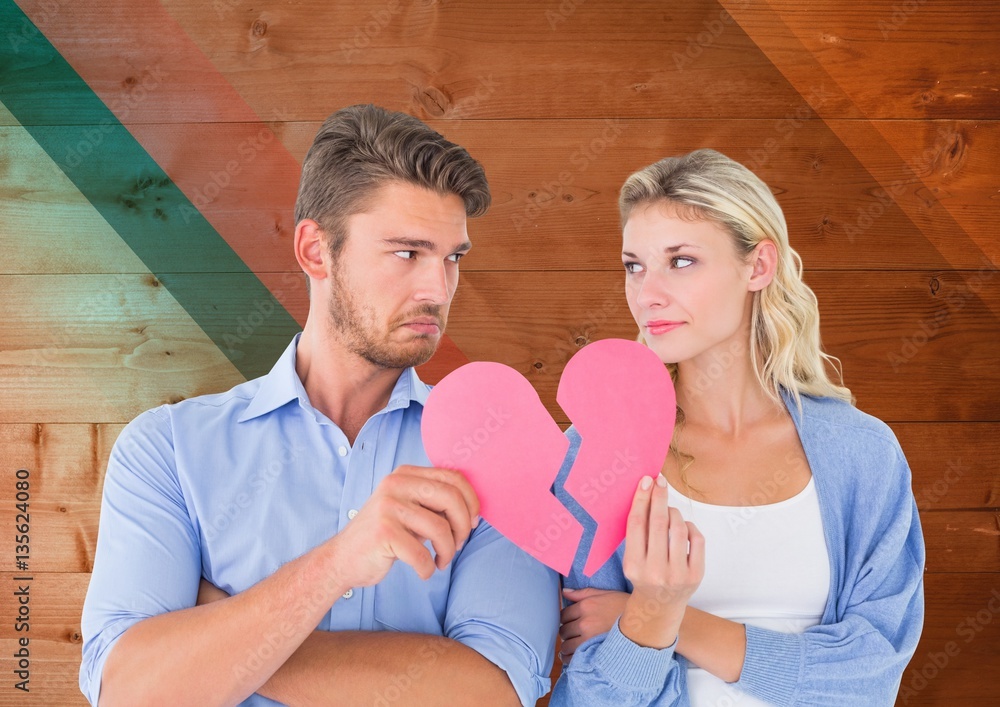 Sad couple looking each other while holding broken hearts Sad couple looking each other while holding broken hearts