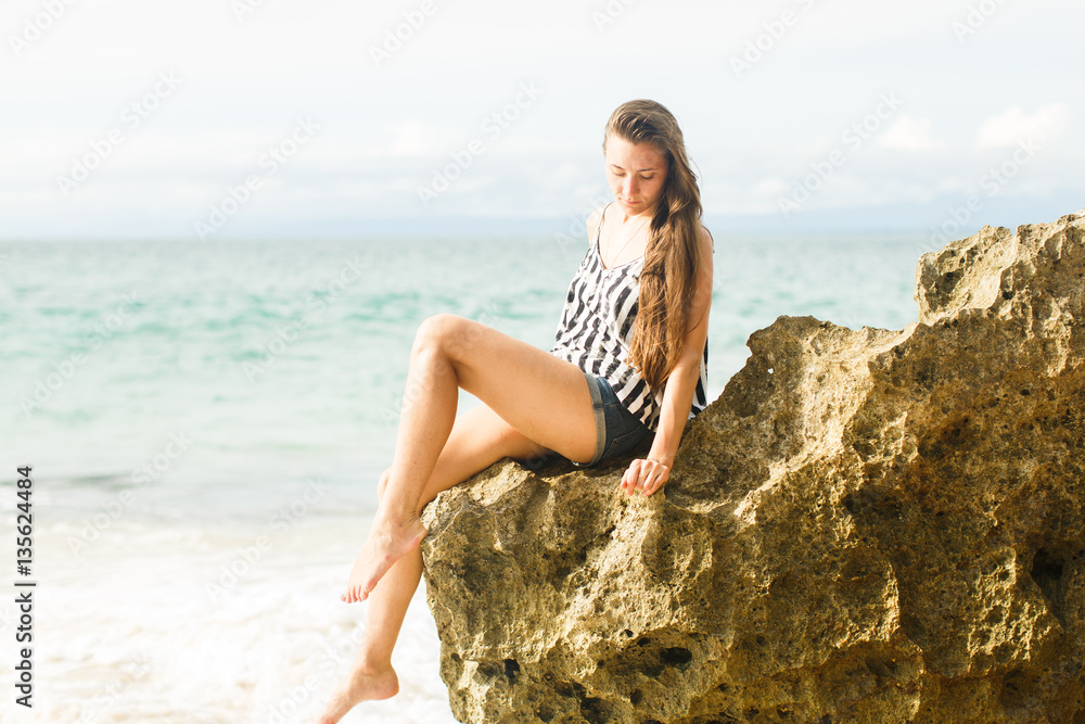 girl walking near ocean and rocks at summer