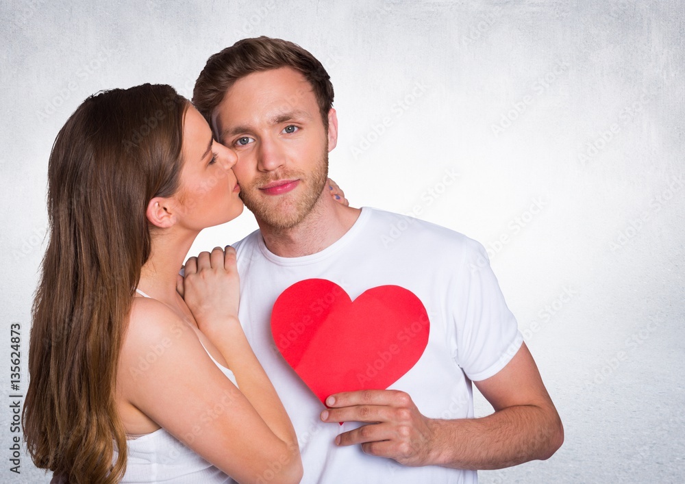 Woman kissing man while holding heart