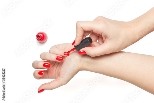 Canvas Print Woman applying red nail polish her nails manicure on white background isolated