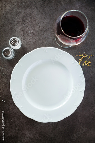 Empty Plate and Red Wine glass on a dark restaurant or bar count