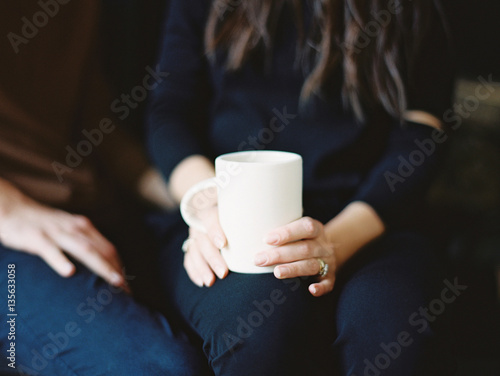 Woman sitting holding a white mug photo