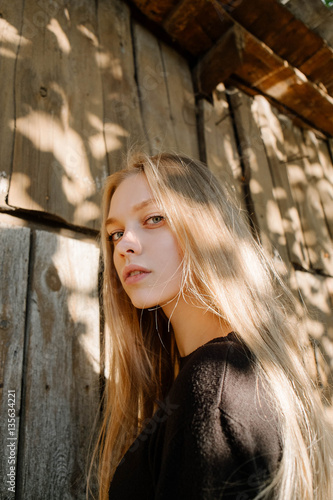 portrait of a beautiful young blonde in the autumn sun outing, against the background of a solar wall, model test