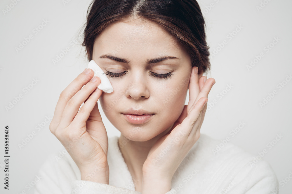 woman wipes her face with a cotton pad, tender skin woman wipes her face with a cotton pad, tender skin