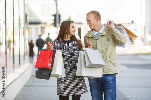 Young couple with shoping bags looking each other