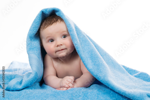 Newborn baby lying down and smiling in a blue towel