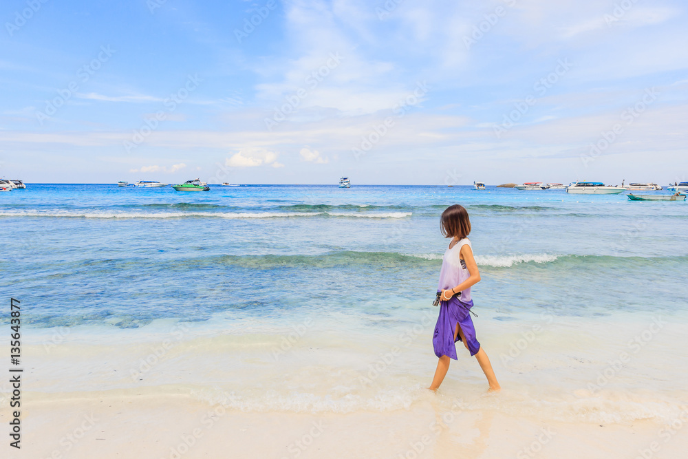 Asian woman in swimsuit walking on beach with happy and beautiful sky above the sea, Similan Island, Similan National Park, Phang Nga, Thailand Asian woman in swimsuit walking on beach with happy and beautiful sky above the sea, Similan Island, Similan National Park, Phang Nga, Thailand
