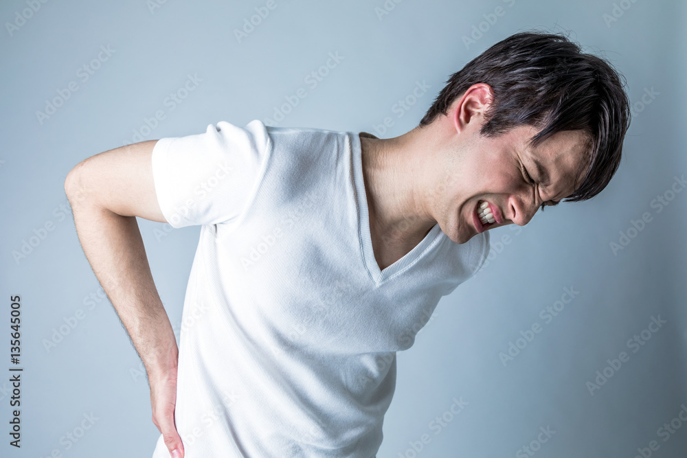 young man having a pain in lower back young man having a pain in lower back