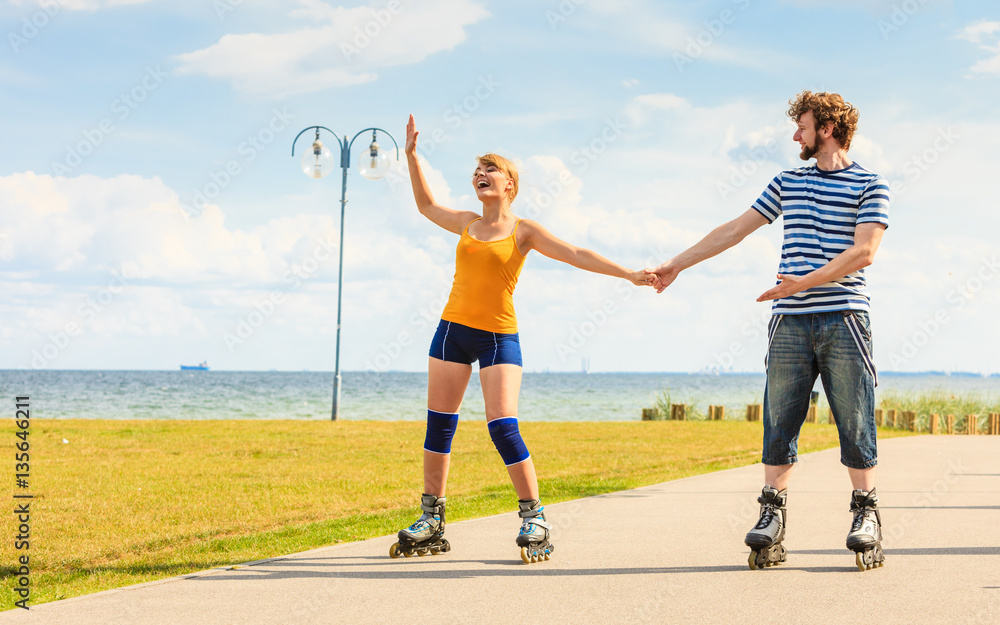 Young couple on roller skates riding outdoors