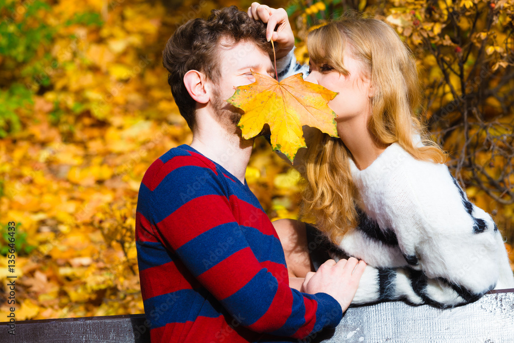 Fototapeta premium couple with maple leaf kissing in autumn park