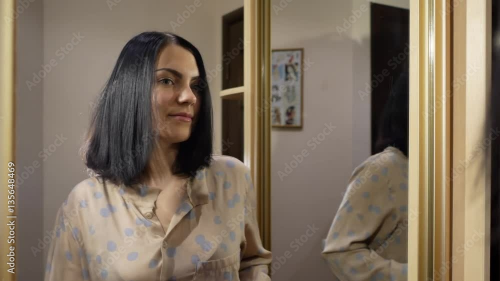 Beautiful young woman ironing her hair near the mirror Beautiful young woman ironing her hair near the mirror