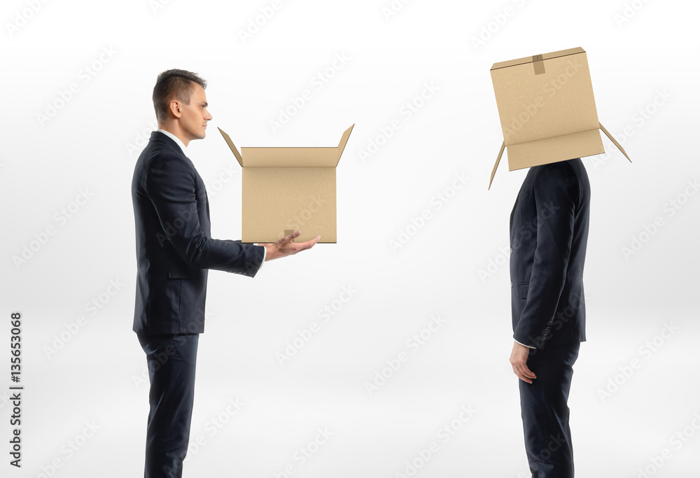 Businessman is passing box to man with cardboard on his head Businessman is passing box to man with cardboard on his head