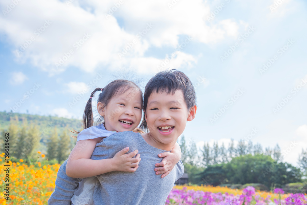 Asian brother holding his sister on his back and smiling togethe Asian brother holding his sister on his back and smiling togethe
