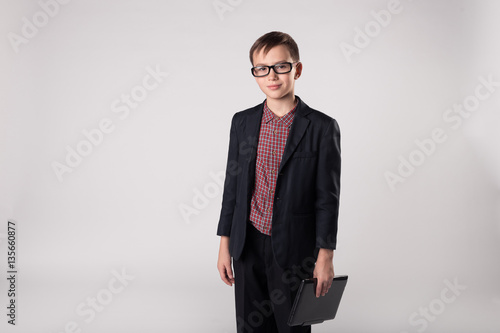 Smiling business kid boss with laptop in his hands