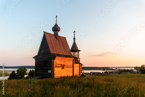 Wooden church on the top of the hill. Vershinino village sunset view. Arkhangelsk region, Northern Russia.