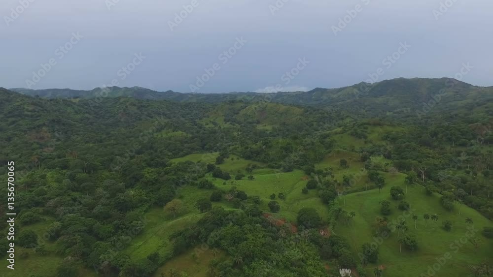 Aerial view of green hills and mountains and a small city at the sea coast Aerial view of green hills and mountains and a small city at the sea coast