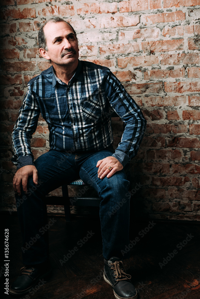 Handsome middle aged man is dressed in a casual clothing. Red brick wall background. Handsome middle aged man is dressed in a casual clothing. Red brick wall background.