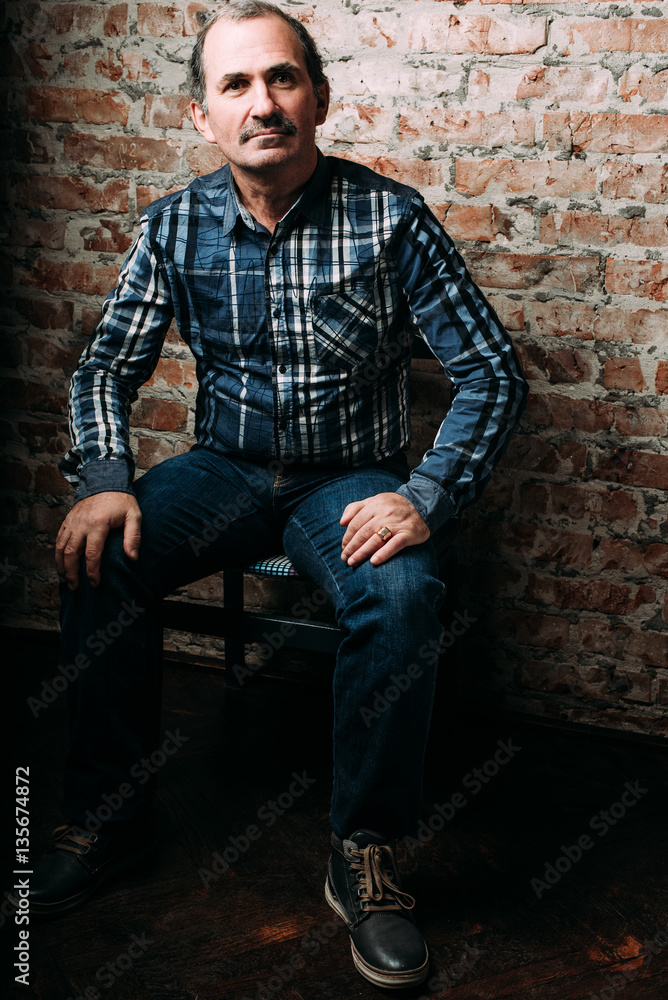 Handsome middle aged man is dressed in a casual clothing. Red brick wall background. Handsome middle aged man is dressed in a casual clothing. Red brick wall background.