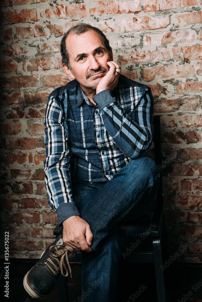 Handsome middle aged man is dressed in a casual clothing. Red brick wall background. Handsome middle aged man is dressed in a casual clothing. Red brick wall background.