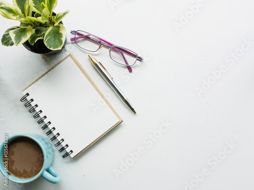 Top view work place of coffee mug, blank note book, pen and glas