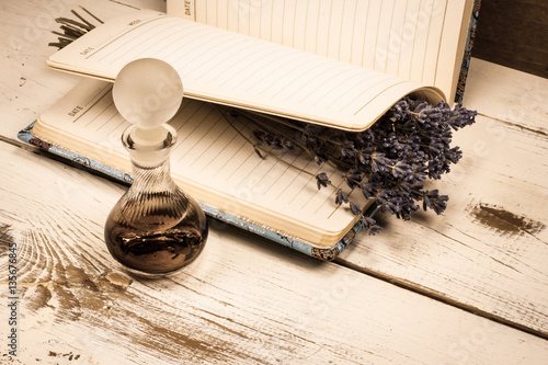 Still life vintage picture, old perfume bottle and a bunch of dried lavender on a journal.