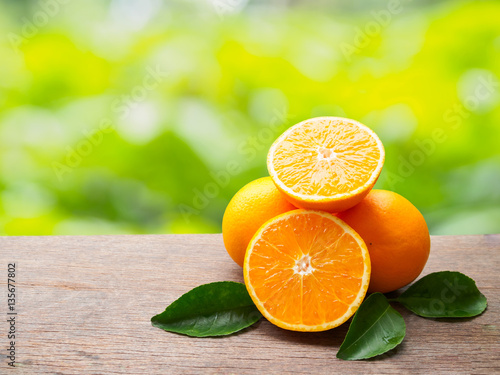 Pile orange fruit and orange slice with gren leaf on wooden tabl