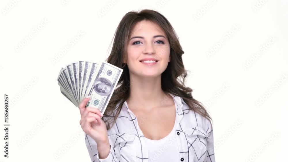 Happy young woman holding money in her hands and pointing finger away while standing isolated on white Happy young woman holding money in her hands and pointing finger away while standing isolated on white