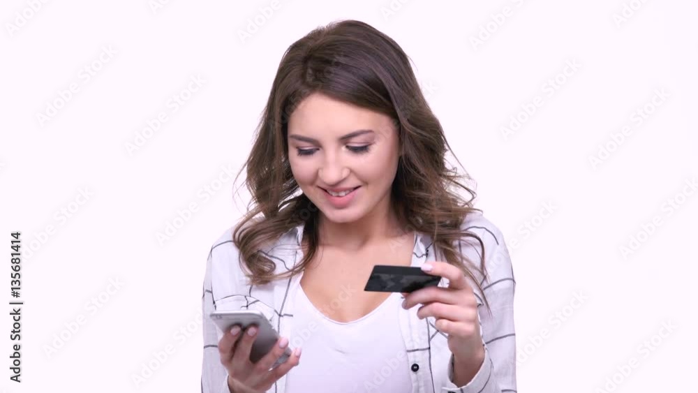 Happy smiling woman paying for her purchase with credit card and mobile phone isolated Happy smiling woman paying for her purchase with credit card and mobile phone isolated