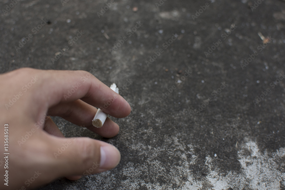 Man hand holding a cigarette with smoke on cement background. Man hand holding a cigarette with smoke on cement background.
